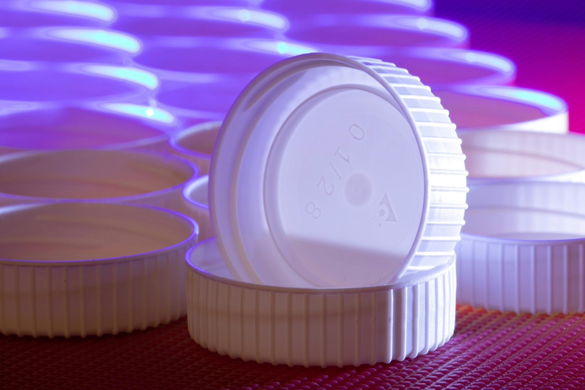 Disposición estética de tapas de plástico blanco con llamativa iluminación azul y violeta.